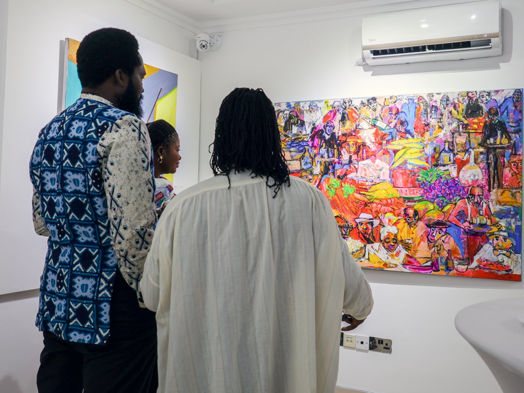 Visitors taking in a large painting of a crowded feast