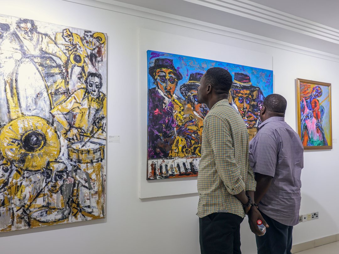 Visitors looking at a gold and white painting of a horn section