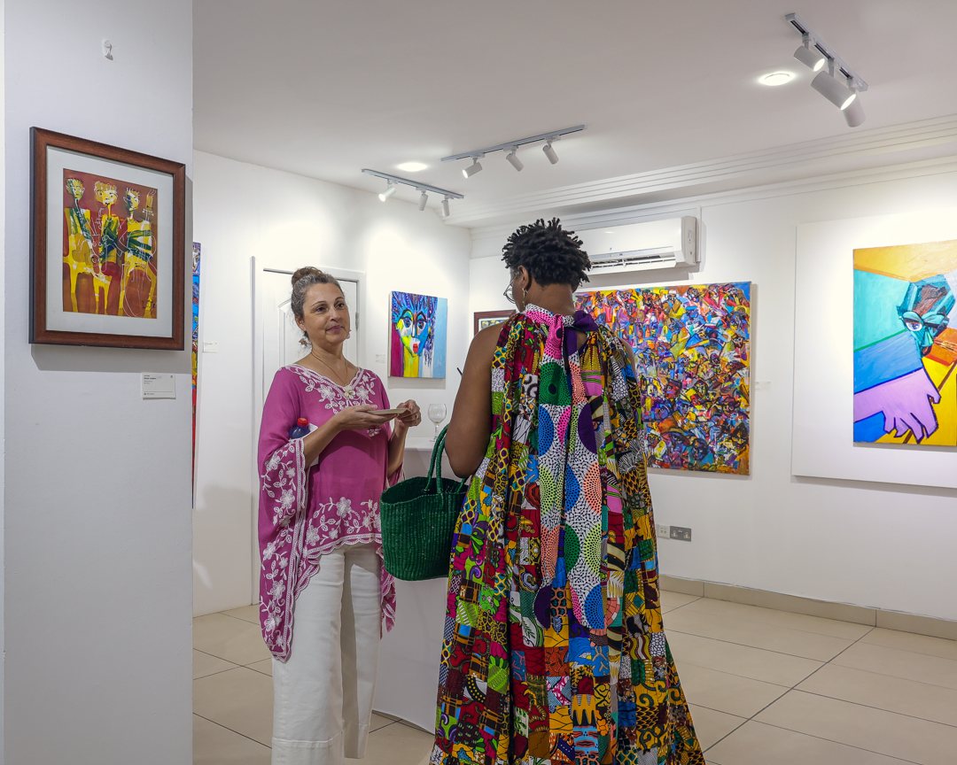 Two guests talking beside a framed work on paper